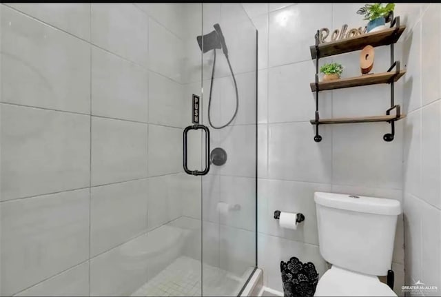 bathroom with toilet, a shower with door, and tile walls