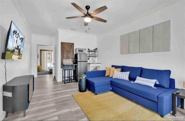 living room with hardwood / wood-style floors, ceiling fan, and ornamental molding