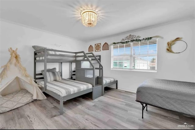 bedroom featuring crown molding, hardwood / wood-style floors, and a notable chandelier