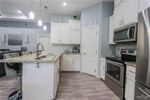 kitchen featuring white cabinetry, sink, stainless steel appliances, and decorative light fixtures