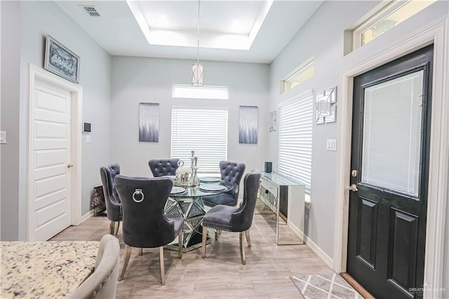 dining space featuring light hardwood / wood-style floors and a raised ceiling