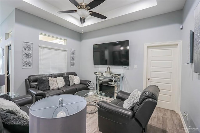 living room with a fireplace, light hardwood / wood-style floors, ceiling fan, and a healthy amount of sunlight