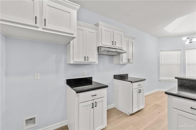 kitchen featuring a skylight, light hardwood / wood-style floors, and white cabinets