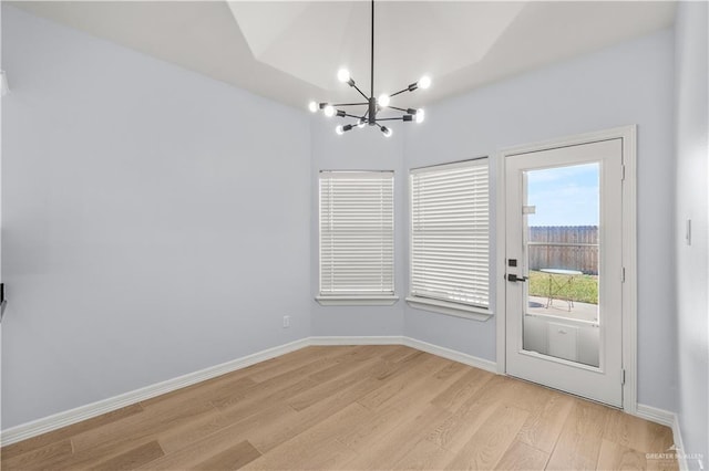 doorway to outside with an inviting chandelier and light hardwood / wood-style flooring