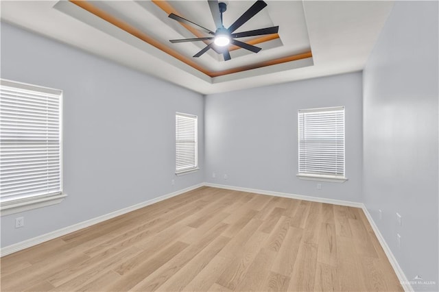 unfurnished room featuring light hardwood / wood-style floors, a raised ceiling, and ceiling fan