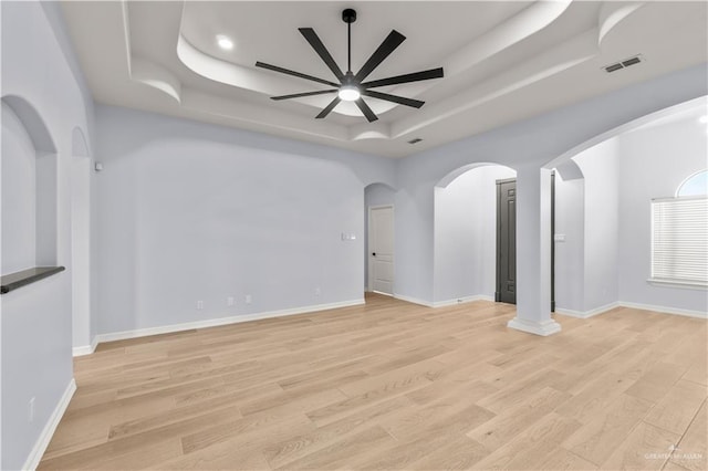 unfurnished living room featuring ceiling fan, a raised ceiling, and light wood-type flooring