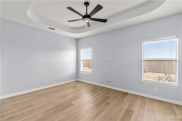 unfurnished room with ceiling fan, a raised ceiling, and light hardwood / wood-style flooring