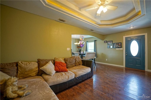 living room featuring ceiling fan with notable chandelier, dark hardwood / wood-style flooring, and a raised ceiling