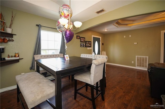 dining room with a raised ceiling and dark hardwood / wood-style flooring