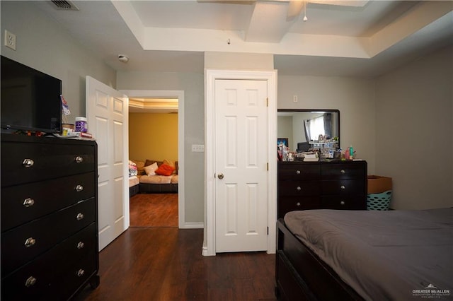 bedroom with a tray ceiling, ceiling fan, and dark wood-type flooring