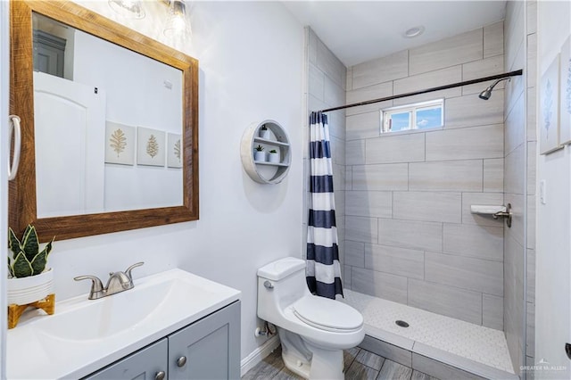 bathroom featuring a tile shower, toilet, and vanity