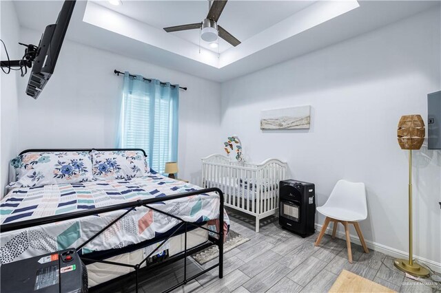 bedroom with a ceiling fan, a tray ceiling, wood finished floors, recessed lighting, and baseboards