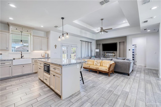 kitchen with visible vents, wood finish floors, built in microwave, a ceiling fan, and a sink