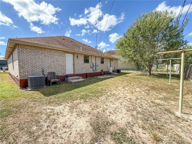 back of property with central AC unit and a lawn