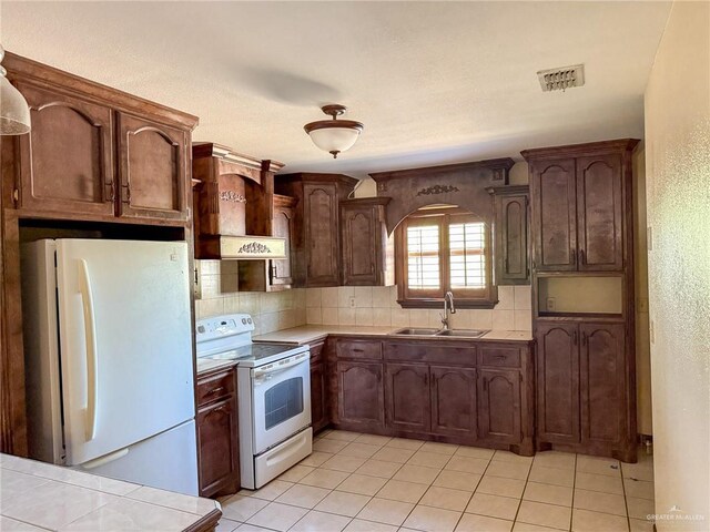 kitchen featuring white appliances, sink, dark brown cabinets, and backsplash