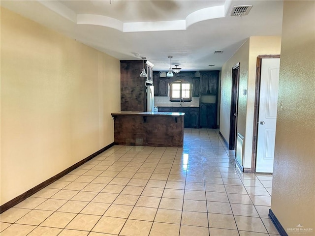 kitchen featuring light tile patterned floors, refrigerator, and kitchen peninsula