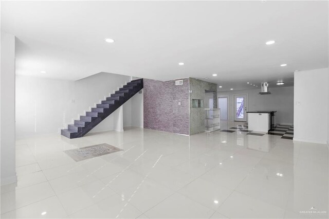 unfurnished living room featuring light tile patterned floors and tile walls