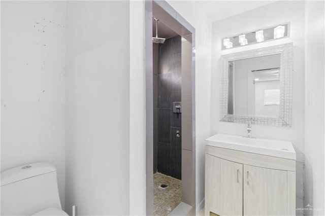 bathroom with toilet, vanity, and tiled shower