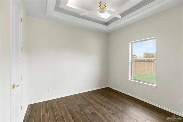 unfurnished room featuring ceiling fan, dark wood-type flooring, and a tray ceiling