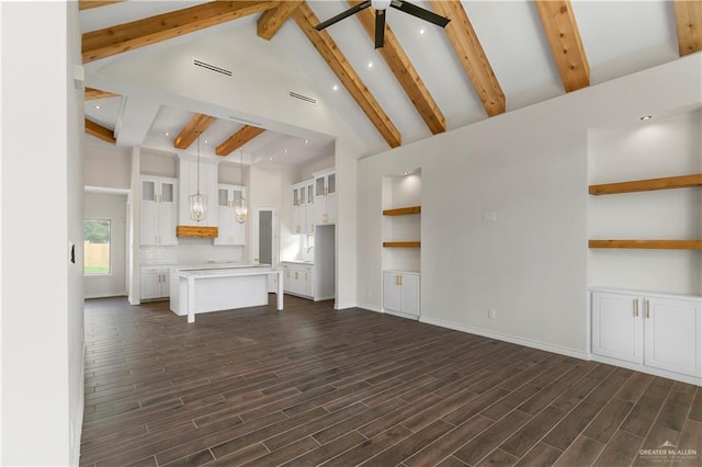 unfurnished living room with beamed ceiling, dark hardwood / wood-style floors, high vaulted ceiling, and ceiling fan