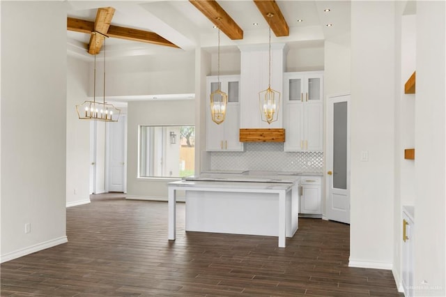 kitchen with a kitchen breakfast bar, backsplash, beam ceiling, white cabinets, and hanging light fixtures