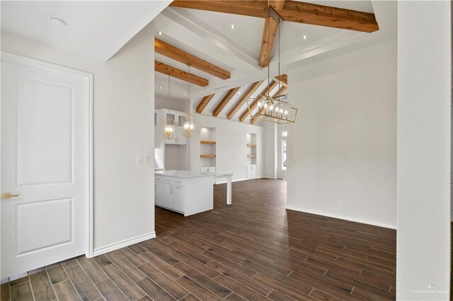 unfurnished living room with beam ceiling, dark hardwood / wood-style flooring, and a chandelier