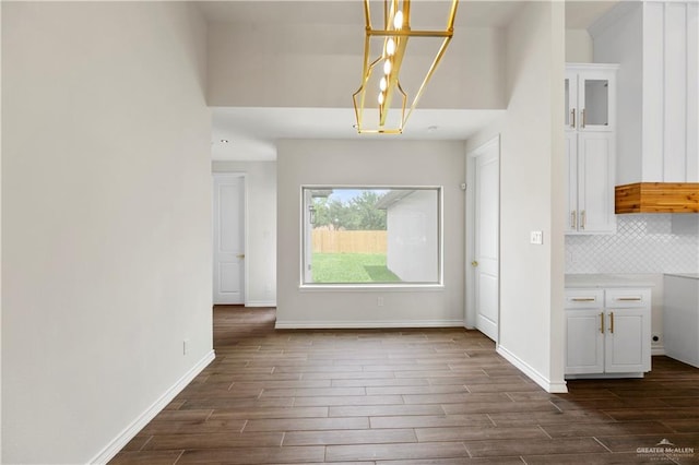 unfurnished dining area featuring a chandelier and dark hardwood / wood-style floors