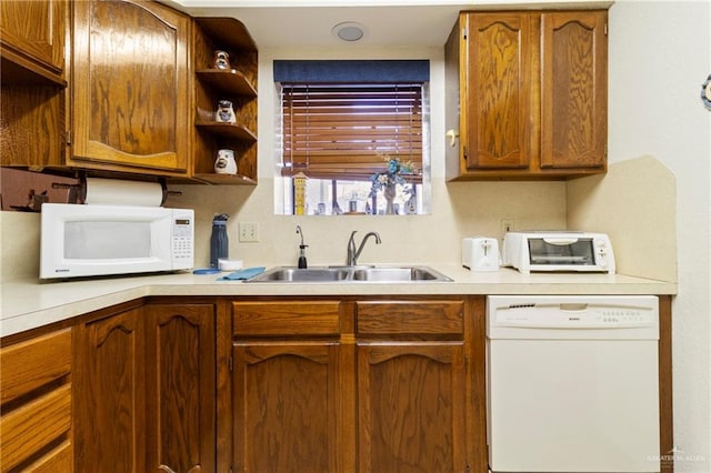 kitchen featuring brown cabinetry, white appliances, light countertops, and a sink