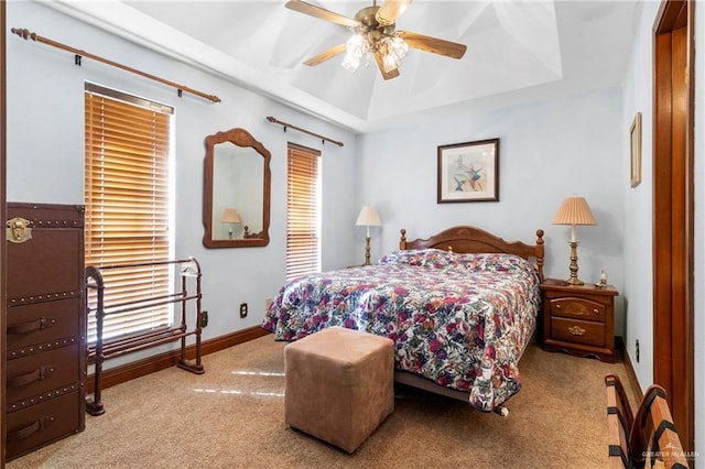 bedroom featuring carpet, a tray ceiling, ceiling fan, and baseboards