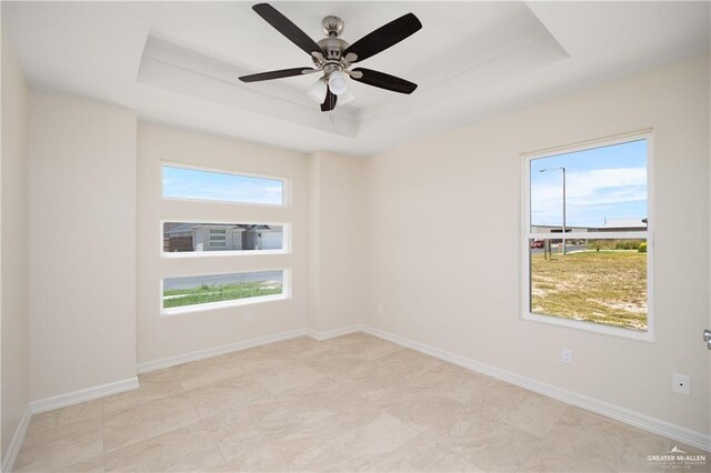 spare room with a tray ceiling and ceiling fan