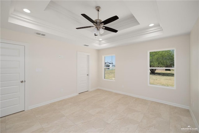 unfurnished room featuring plenty of natural light, ceiling fan, and a raised ceiling