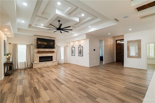 unfurnished living room with a stone fireplace, ceiling fan, and light hardwood / wood-style floors