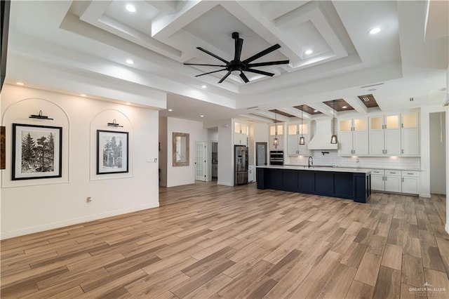 kitchen featuring backsplash, an island with sink, decorative light fixtures, white cabinets, and appliances with stainless steel finishes