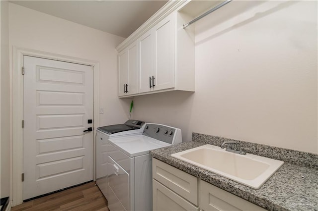 laundry room featuring washer and dryer, dark hardwood / wood-style floors, cabinets, and sink