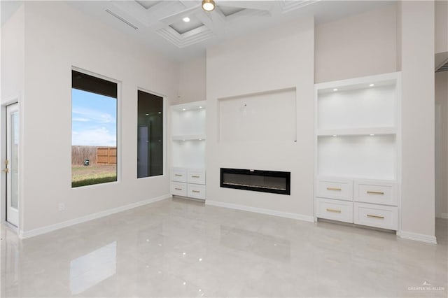 unfurnished living room with a high ceiling, coffered ceiling, baseboards, built in features, and marble finish floor