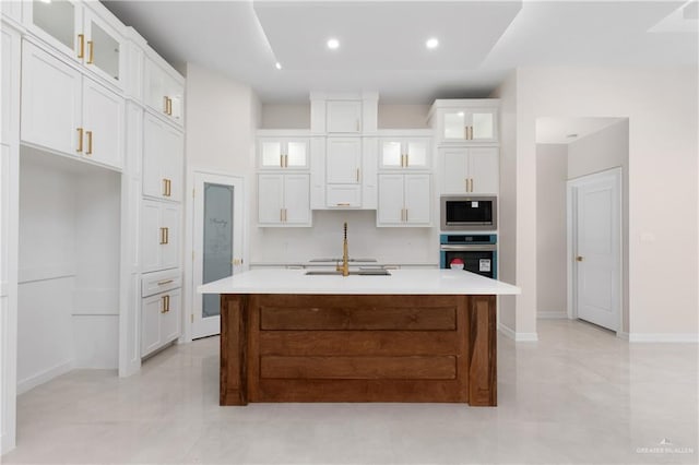 kitchen with a kitchen island with sink, appliances with stainless steel finishes, white cabinets, and light countertops