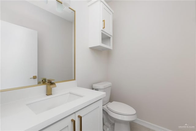 bathroom with baseboards, vanity, and toilet