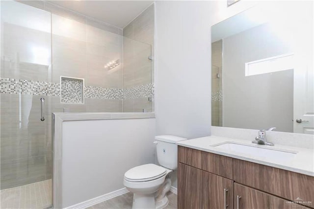 bathroom featuring vanity, a shower with shower door, and toilet