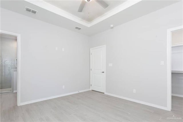 unfurnished bedroom featuring ceiling fan, a spacious closet, and light hardwood / wood-style flooring