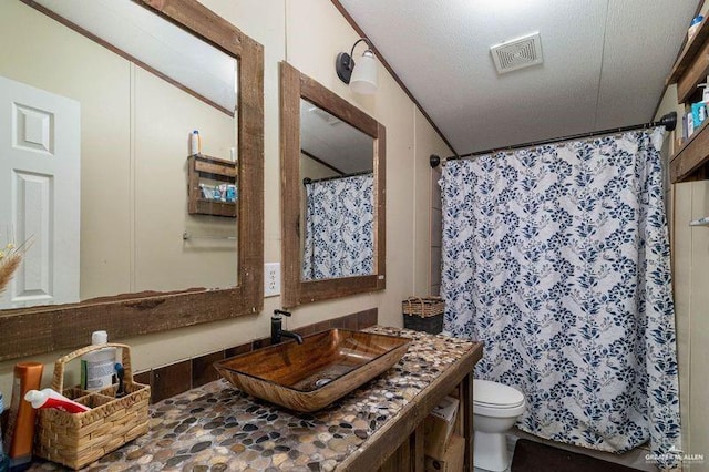 full bathroom featuring toilet, visible vents, a textured ceiling, and vanity