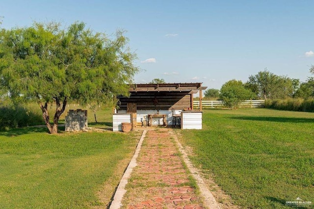 view of yard with an outbuilding, a rural view, and fence