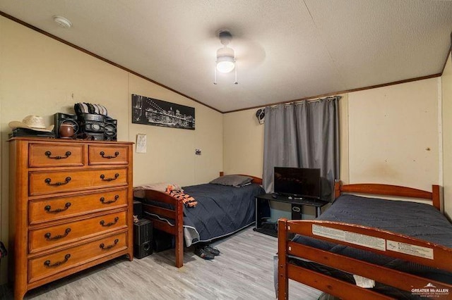 bedroom with vaulted ceiling, ornamental molding, light wood finished floors, and a textured ceiling