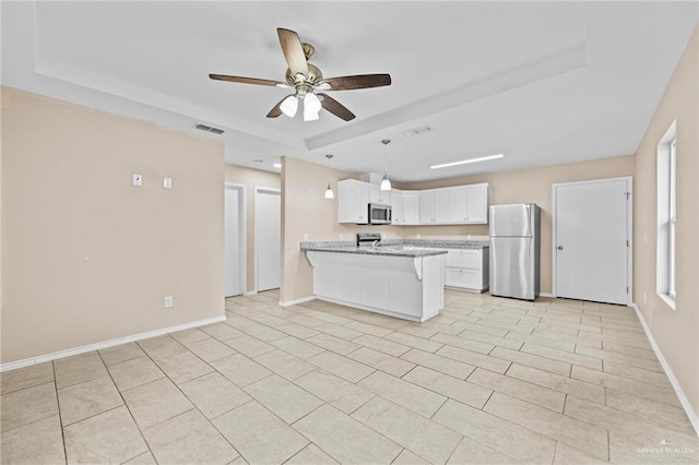 kitchen featuring stainless steel appliances, white cabinetry, a raised ceiling, and kitchen peninsula