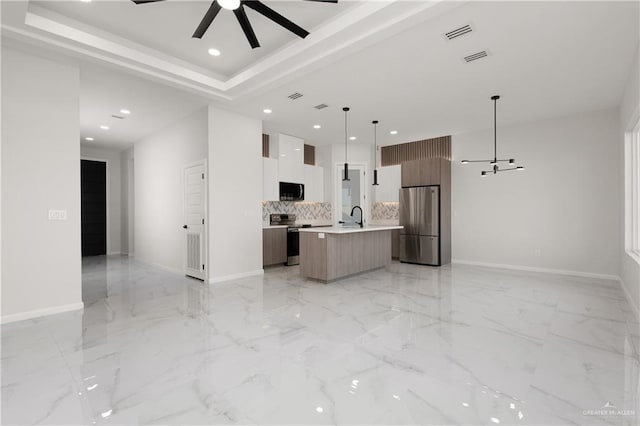 kitchen featuring appliances with stainless steel finishes, backsplash, a kitchen island with sink, ceiling fan, and hanging light fixtures