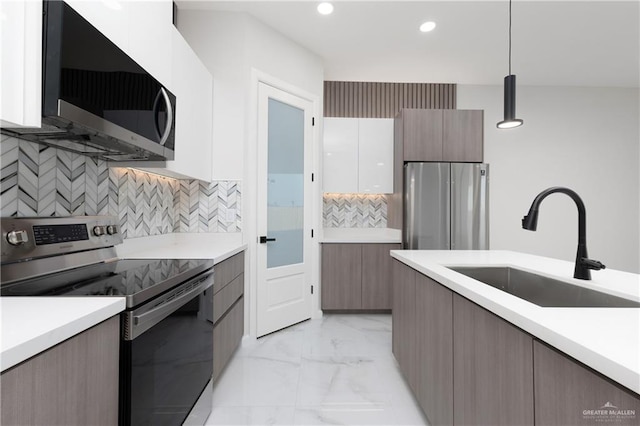 kitchen featuring white cabinetry, sink, stainless steel appliances, backsplash, and pendant lighting