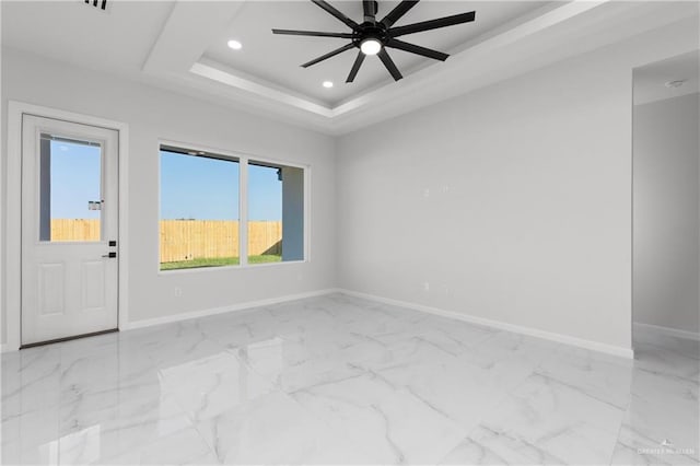 spare room with a raised ceiling and ceiling fan