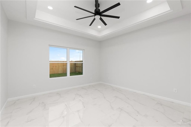 unfurnished room featuring ceiling fan and a tray ceiling