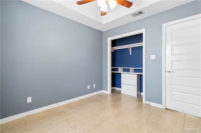 unfurnished bedroom featuring a tray ceiling, a closet, and ceiling fan