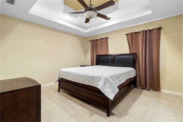 bedroom with ceiling fan, a raised ceiling, and light tile patterned floors