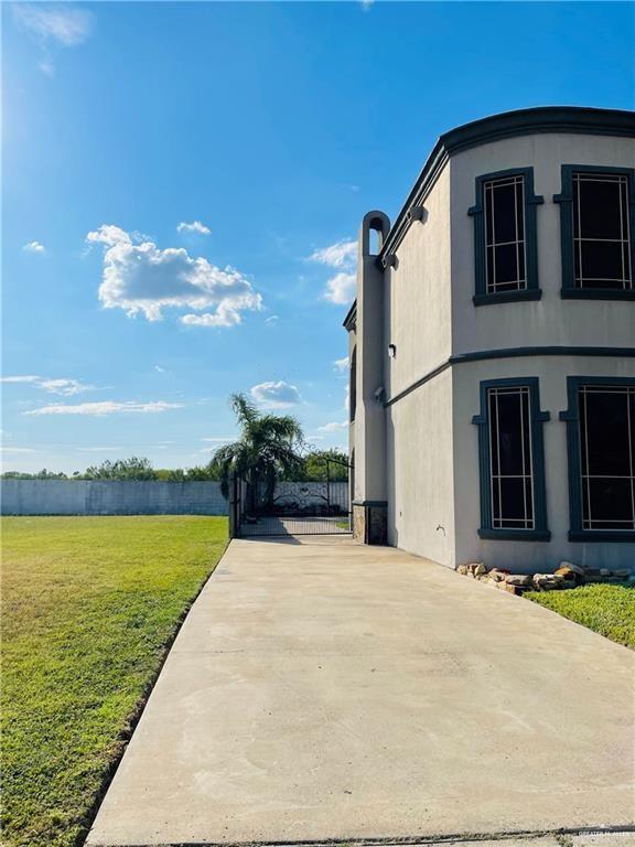 view of property exterior with a yard, stucco siding, and driveway